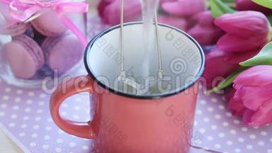 在粉红色陶瓷杯、粉红色郁金香<strong>和</strong>红杏仁的茶袋上倒入热开水
